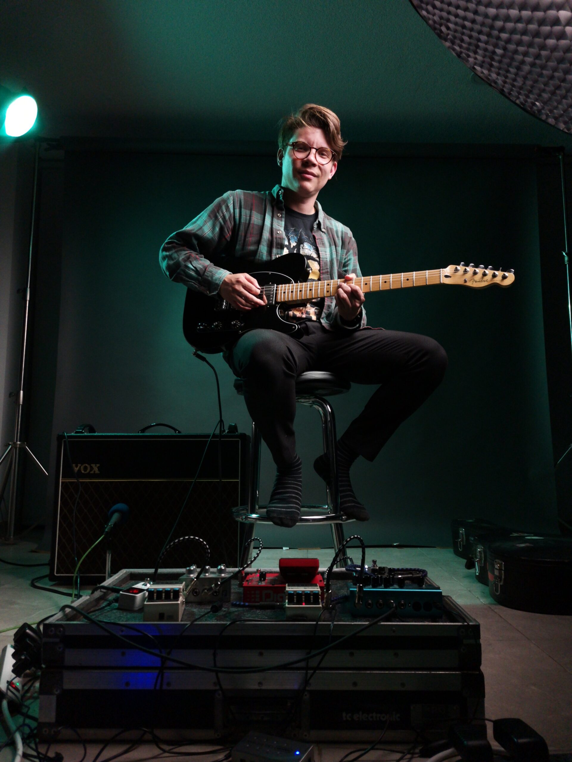 Irving Perez playing guitar in the studio, pedalboard in frame